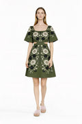 May include: Olive green dress with a square neckline and short sleeves. The dress features a floral pattern in black and white. The waist has a cut-out design. The model is wearing pink fuzzy slippers.