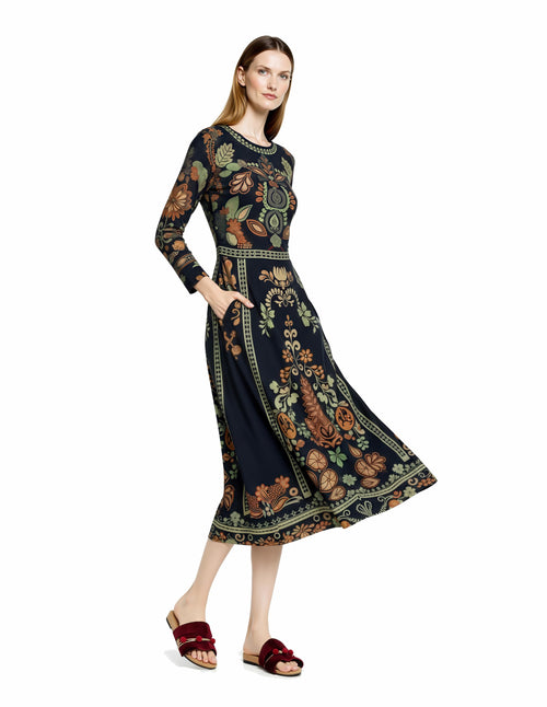 May include: A long-sleeved, navy blue dress with a floral and leaf pattern in shades of orange, green, and brown. The dress has a round neckline, fitted waist, and pockets. The model is wearing burgundy sandals. __etsy:7972532309