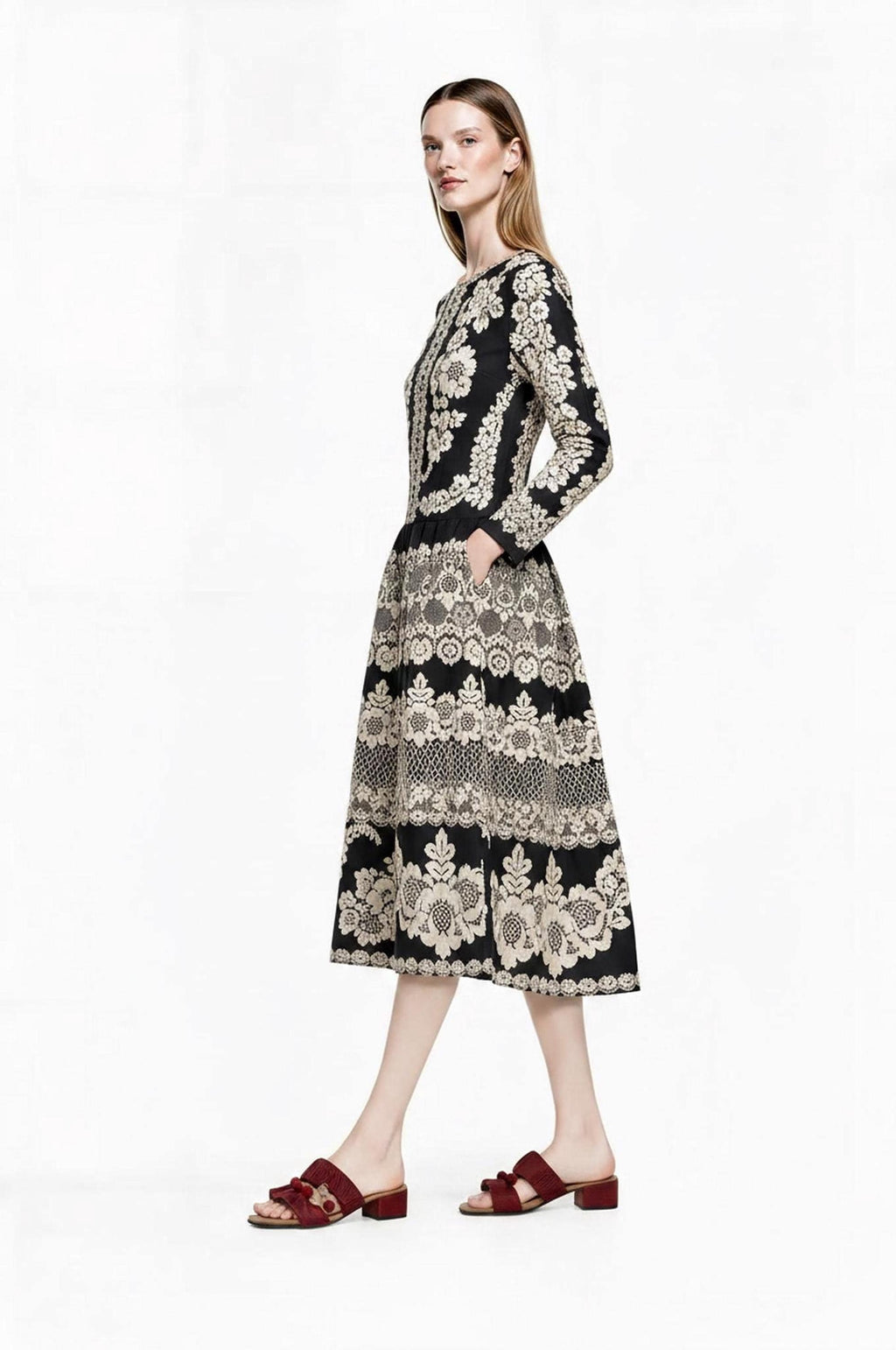 Side view of the model walking in profile, showcasing the pocket and pattern of the black and ivory dress.