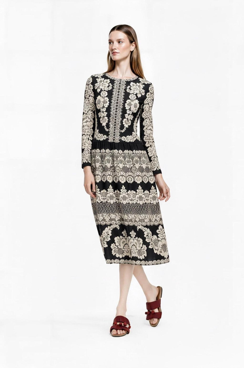 Full-length front view of the model standing with hands resting near the waist of the black floral midi dress.