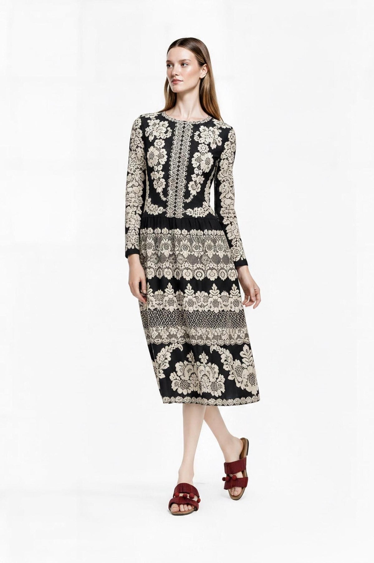 Full-length front view of the model standing with hands resting near the waist of the black floral midi dress.