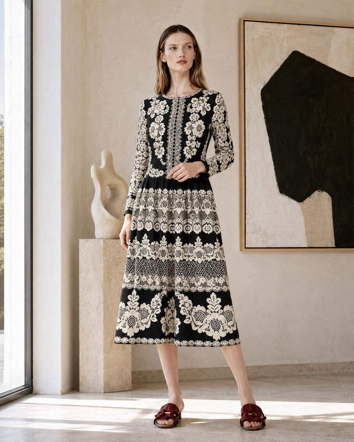 Indoor shot of the model standing in a gallery-like room with a painting and abstract sculpture behind her.