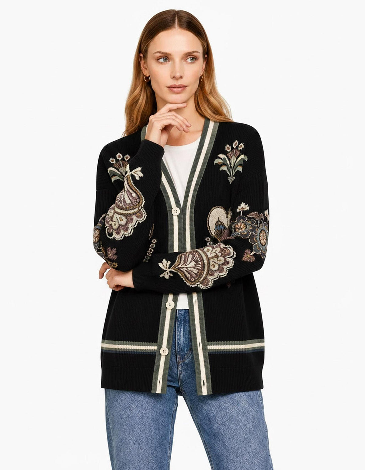 A portrait of the model with hand under chin, wearing the black cardigan with olive and white striped trim over a white shirt.