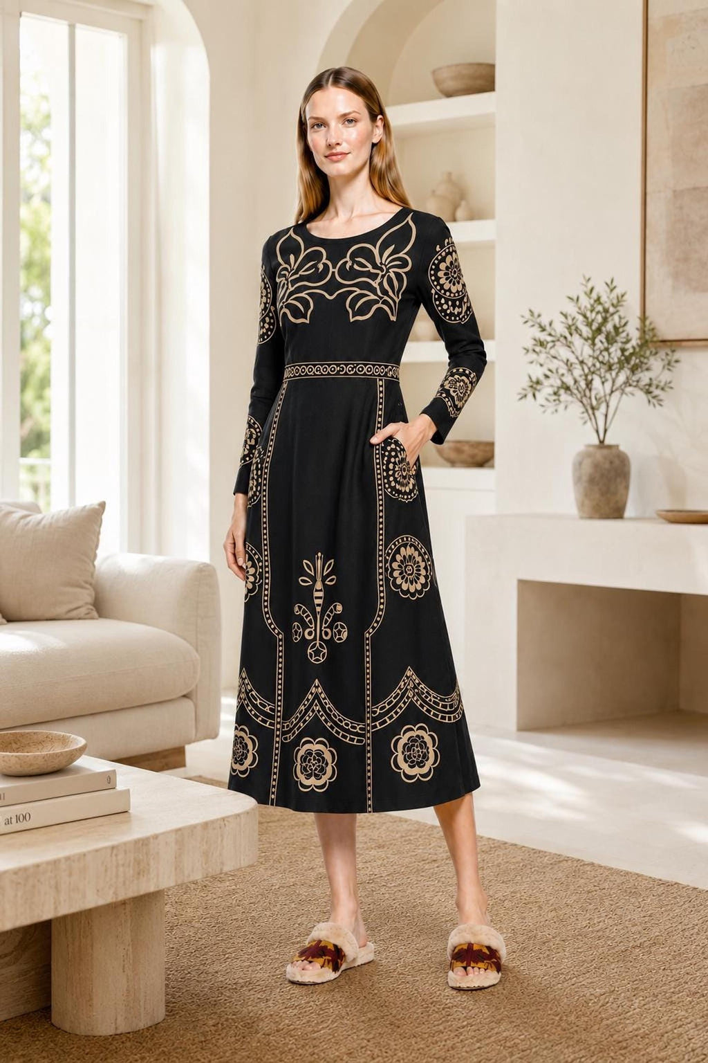 A model poses in an indoor living room setting wearing the black midi dress with beige floral print.
