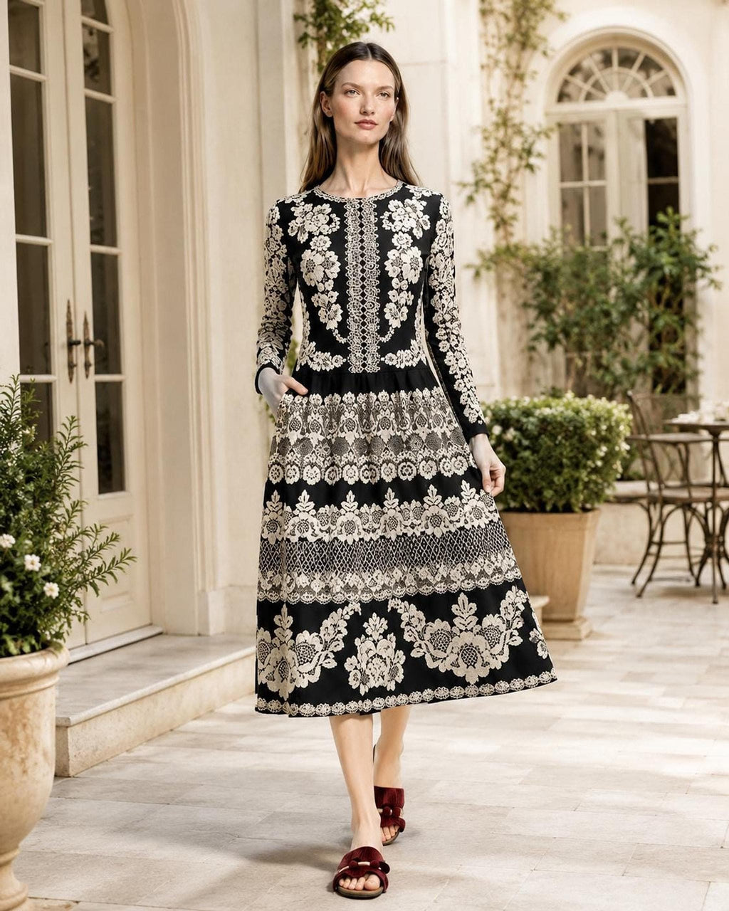 Outdoor shot of the model walking down a stone path in front of a building wearing the black floral midi dress.