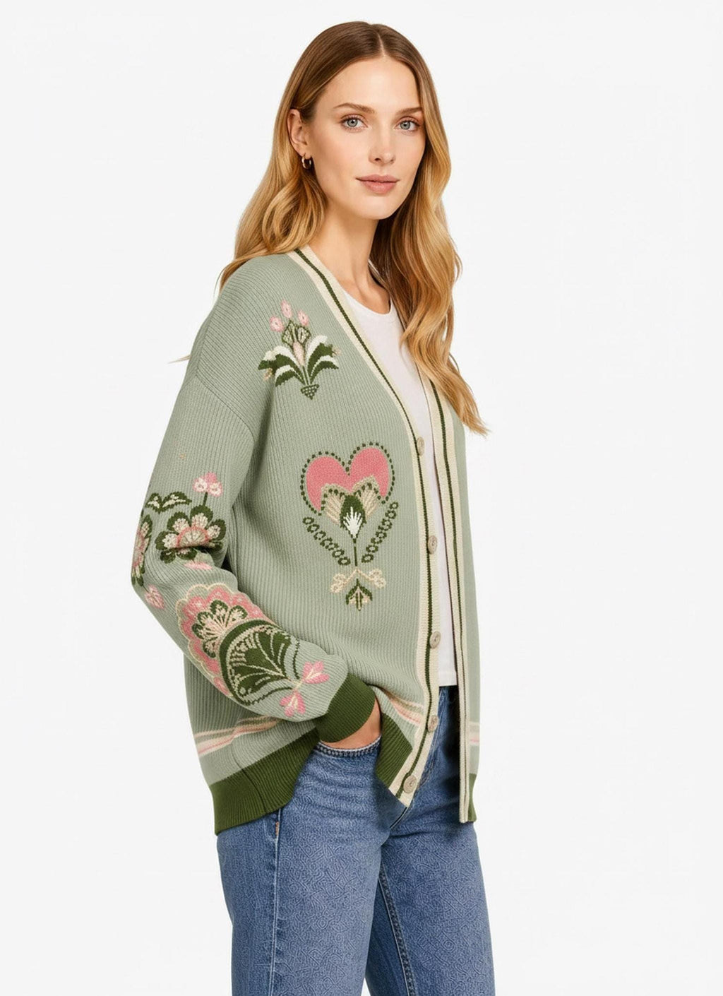 A side-angle view of a woman wearing a sage green knit cardigan with ornate pink floral motifs along the sleeve and torso.