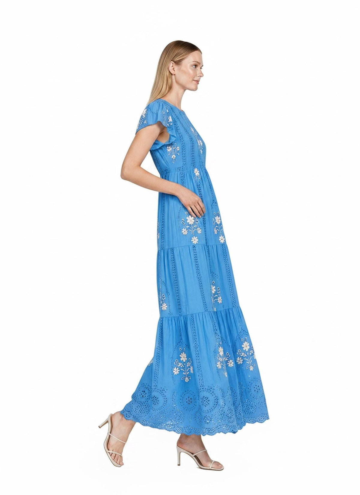 A model stands in profile facing right, wearing a vibrant blue maxi dress featuring tiered skirts, eyelet details, and flutter sleeves.
