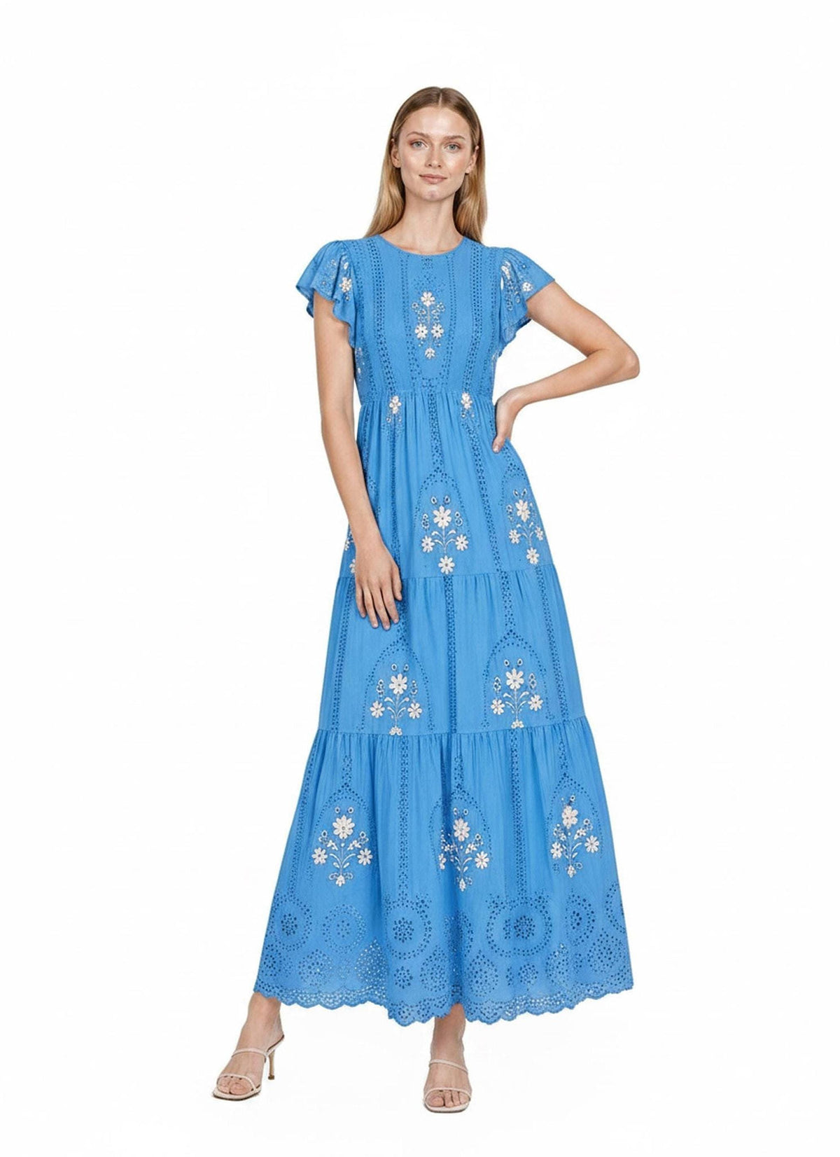A front-facing view of a model wearing a bright blue tiered maxi dress adorned with white floral embroidery and flutter sleeves.