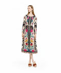 A model stands facing forward in a long-sleeve midi dress featuring a cream base with colorful folk-style floral embroidery patterns and a black panel down the center.