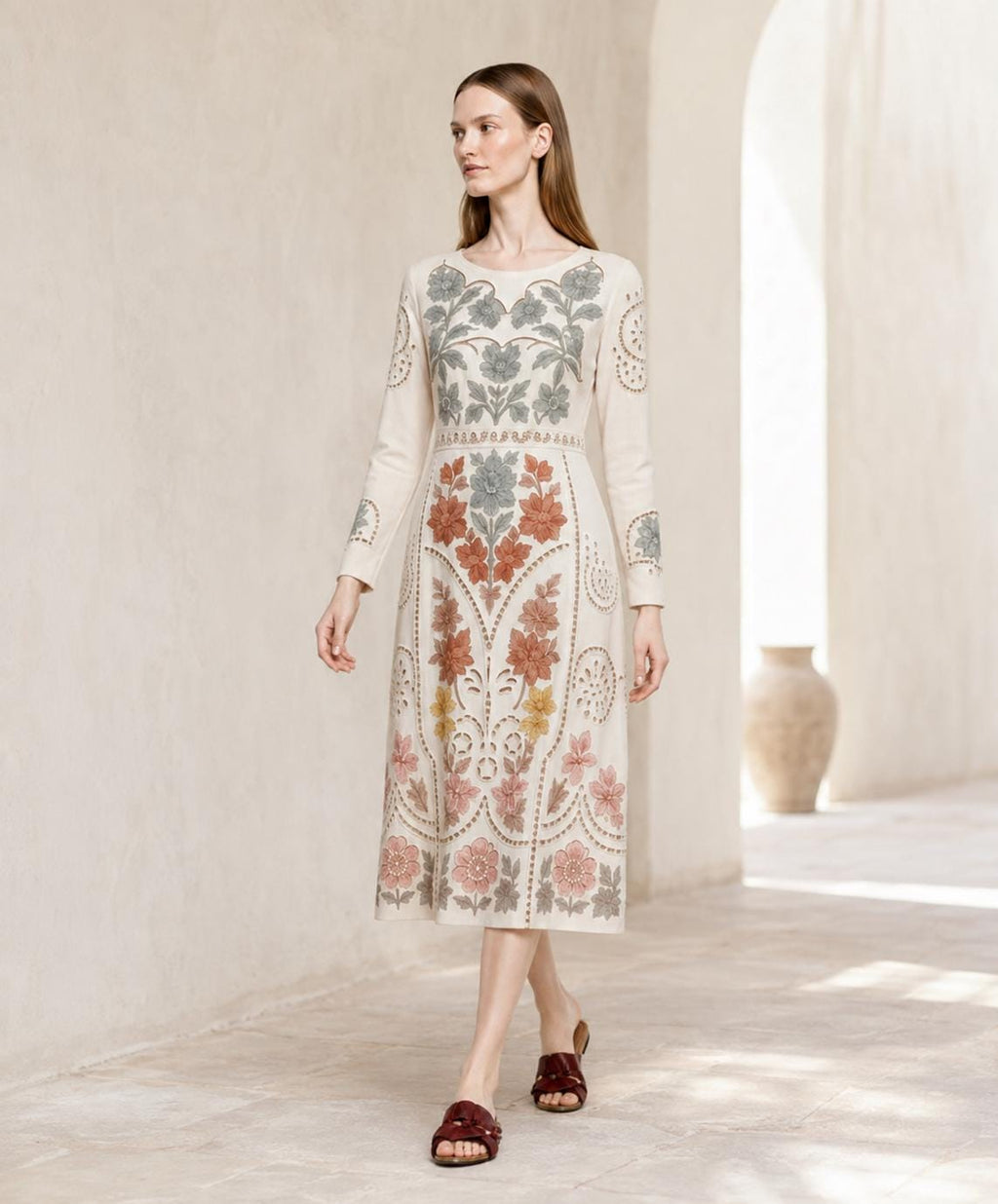 May include: A cream-colored midi dress featuring long sleeves and a round neckline. The garment is decorated with intricate floral embroidery in shades of sage green, terracotta, mustard yellow, and dusty pink, extending from the bodice to the hem.